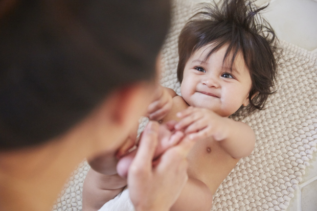 Close over shoulder view of woman playing with baby daughters feet on bathroom floor