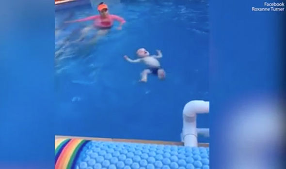 Swimming instructor teaches baby how to float