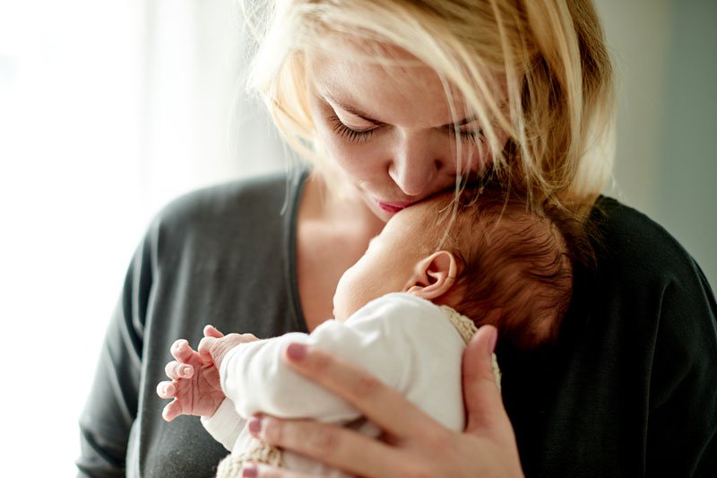 Mother kissing newborn's head