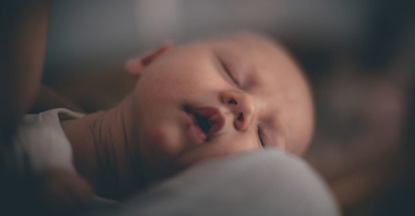 sleeping baby lying on mother's shoulder